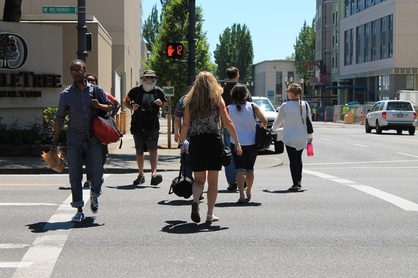 Eight adults crossing a street at a Portland intersection on a sunny day with the pedestrian signal counting down 12 seconds.