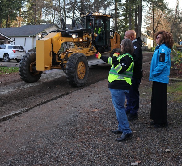 Yates talks with Mapps and Williams about gravel streets viewing a grader in SW Portland