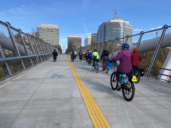 People dressed for rain ride bikes on the Blumenauer Bridge in November 2023