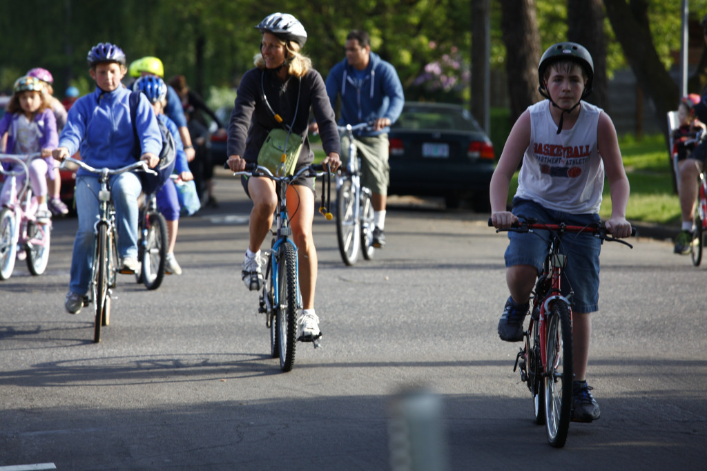 More than 10 youth and adults bike on a neighborhood street together.