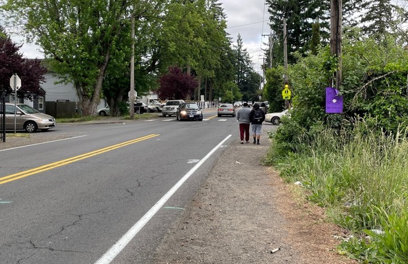 Before: Residents walk along a gravel path adjacent to the road and traveling cars.