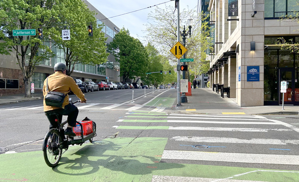 Person riding a cargo bike on SW Broadway at Jefferson Street, looking south