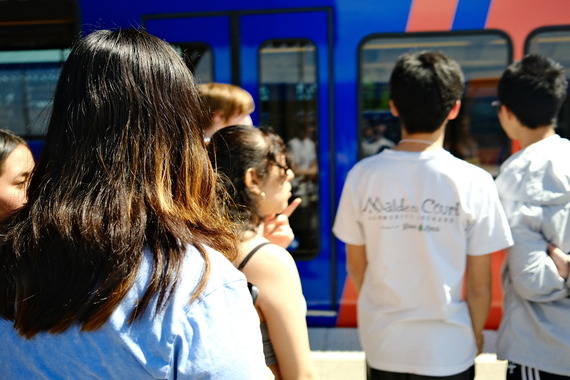 Six high school-aged youth prepare to enter a blue and orange TriMet MAX train.