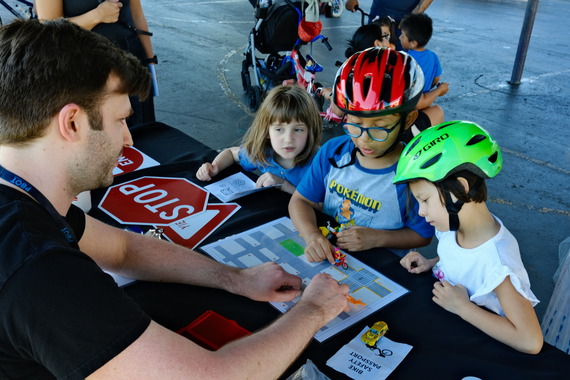 Three children learn about traffic safety at a neighborhood bike fair.