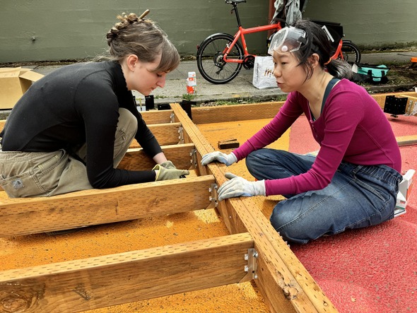 Two women sit and work on building the stage at Rainbow Road.