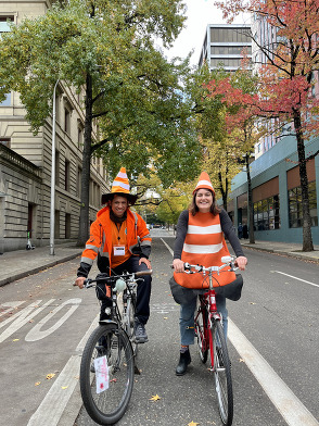 Two Portlanders dressed as traffic cones on bikes.