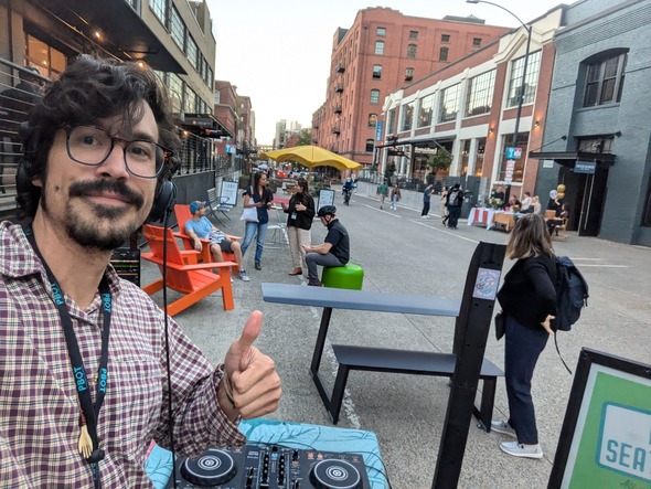 Tyler Smith gives a thumbs up while djing at Lounge Lab, various furniture pieces are visible in the background.