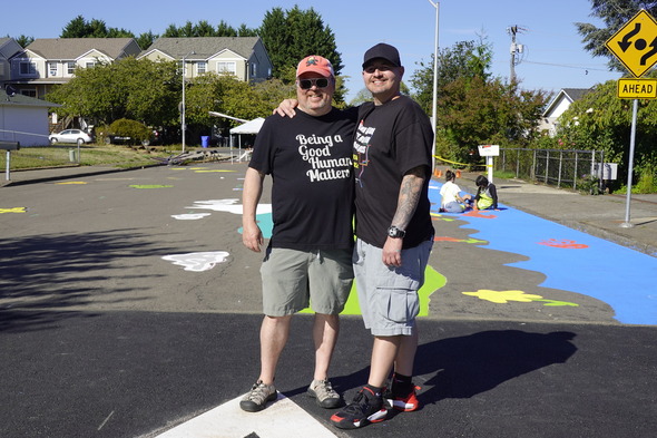 Vic Trillo and Greg Raismen stand arm and arm during the street painting day. Greg shirt reads "being a good human matters"