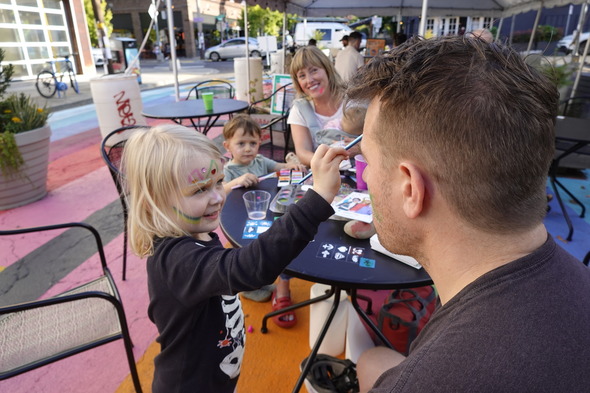 A child paints on the face of her guardian during the Concordia commons celebration.