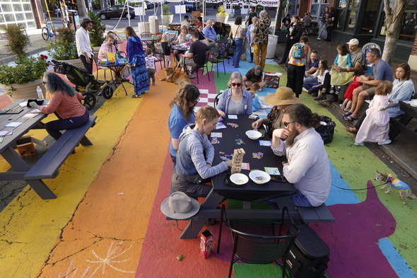 People sit around on picnic benches to play games in the colorfully painted Concordia Commons.