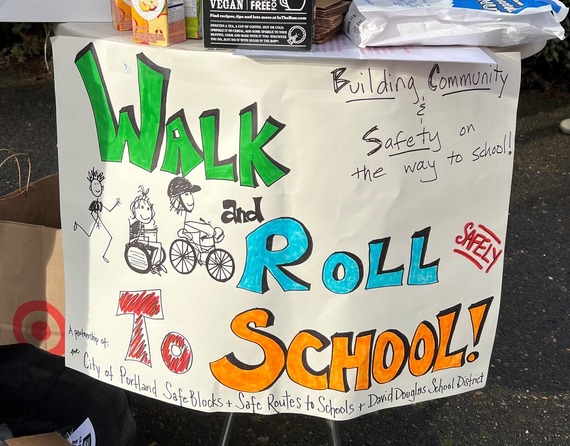 A handmade sign, "Walk and Roll to School!" hangs from a snack table 