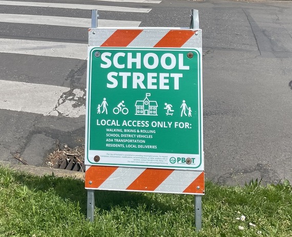 An A-frame green "school street" sign naming the only local access permitted.