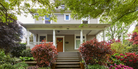 Single-family residential home with a covered porch and varied colorful plants in the yard