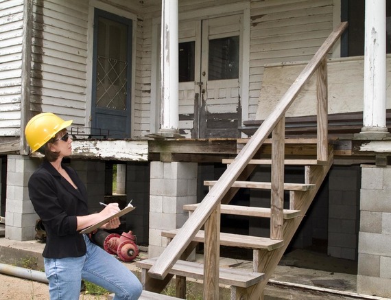 Woman in hard hat inspecting new steps on old house porch