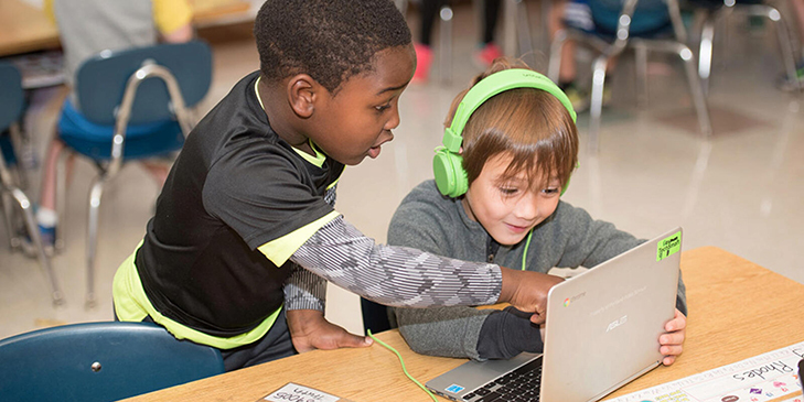 BPS - two kids looking at a chromebook and smiling