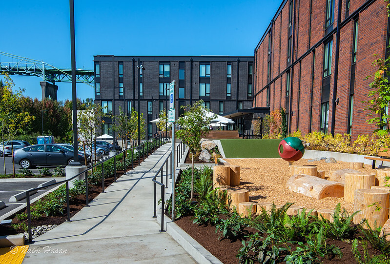 BPS - looking across 4-story brick multifamily building with accessible ramp and play area in front