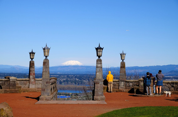 People stand atop Rocky Butte looking north towards a snowcapped Mount St. Helens