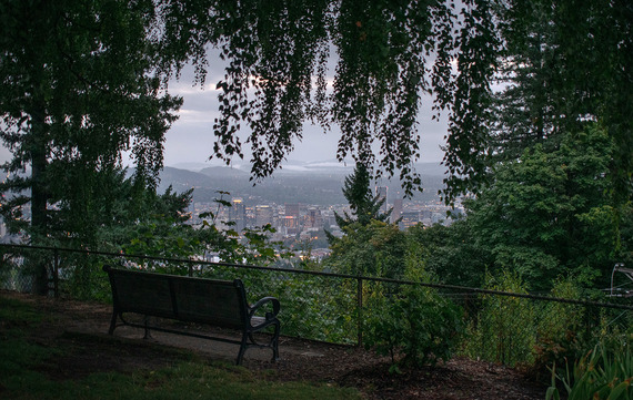 View of downtown Portland from a Pittock Mansion bench on a cloudy evening
