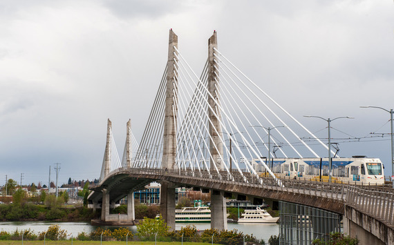Tilikum Crossing bridge with a MAX light rail train going over it and gray skies in the background