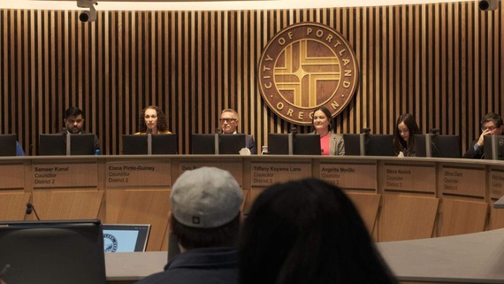 A photo of Councilor Koyama lane in the Council Chambers, seated, between her colleagues.