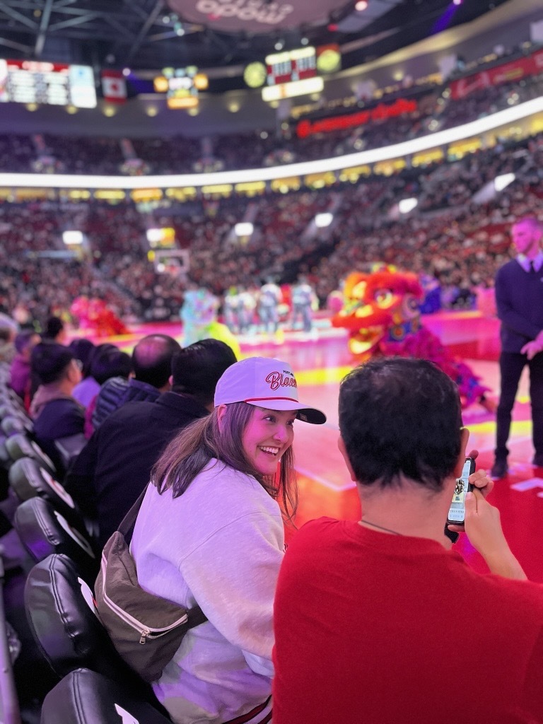 Councilor Koyama Lane sitting courtside with a Blazers hat on