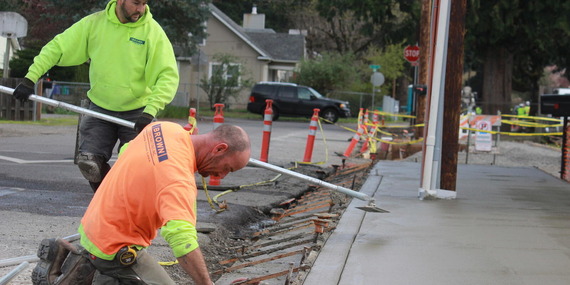 Two concrete workers working on a sidewalk