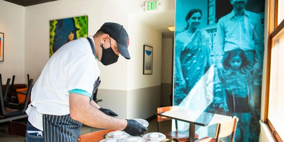 Restaurateur wearing gloves and mask packaging food