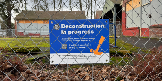 Deconstruction in progress sign posted behind a cyclone fence