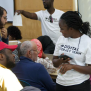 Classroom of diverse people, some wearing t-shirts that say "Digital Literacy Team"