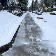 Snowy city street with view of shoveled sidewalk
