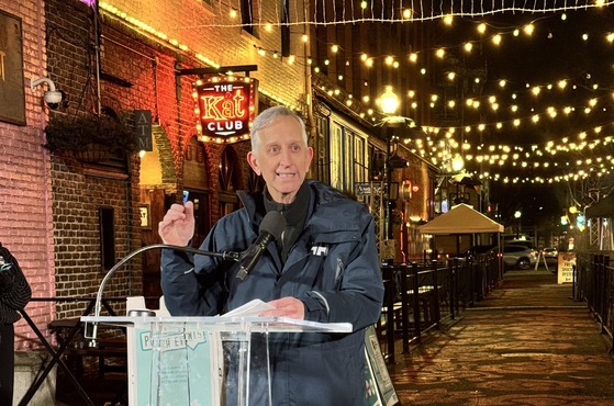 Mayor Keith Wilson speaks at a podium with Ankeny Alley in the background.