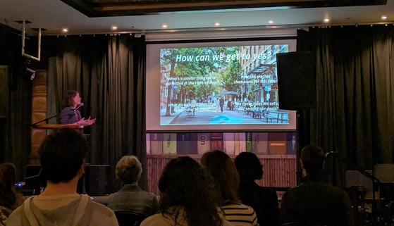 Sarah Figliozzi gives a presentation on street plazas in front of an audience at the streets of possibility event.