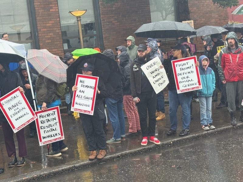 photo of postal workers rally on rainy sidewalk