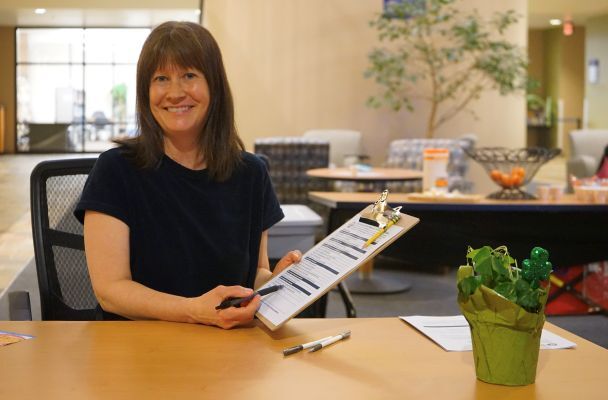 A city employee holds a clipboard and invites residents to share their views about the city budget.