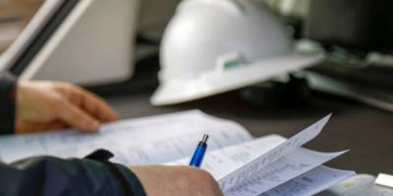 Inspector reviewing plans with hard hat set aside in background