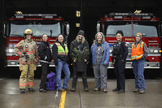 Seven female City of Portland employees stand in a line, wearing various work clothing and gear, such as firefighter protective gear, police uniform