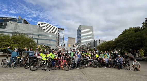 Group of bicyclists pose with their bikes in downtown Portland following a bike bus group ride.