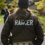 Portland Parks ranger stands with back to the camera and the word "Ranger" on the the back of a brown jacket