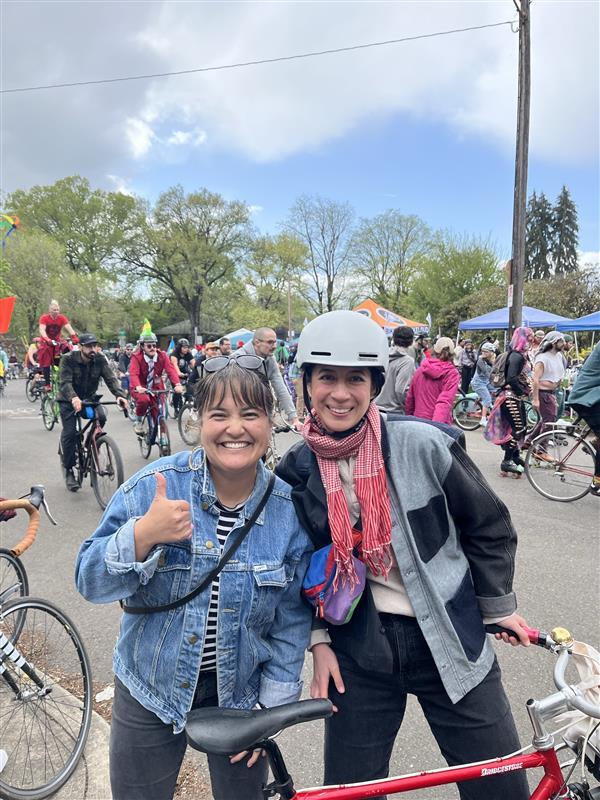 Councilor Koyama Lane gives a thumbs up with a friend behind a bike