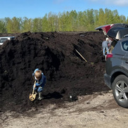 A child digs in a huge compost pile at a PBOT Free Compost Day