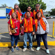 A group of people in high-visibility orange vests standing on the side of the street