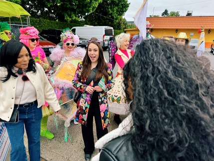 Councilor Morillo wearing a bright floral jacket surrounded by folks wearing flamboyant clothing at a parade