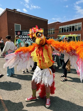 A person wearing a chicken costume at an outdoor event