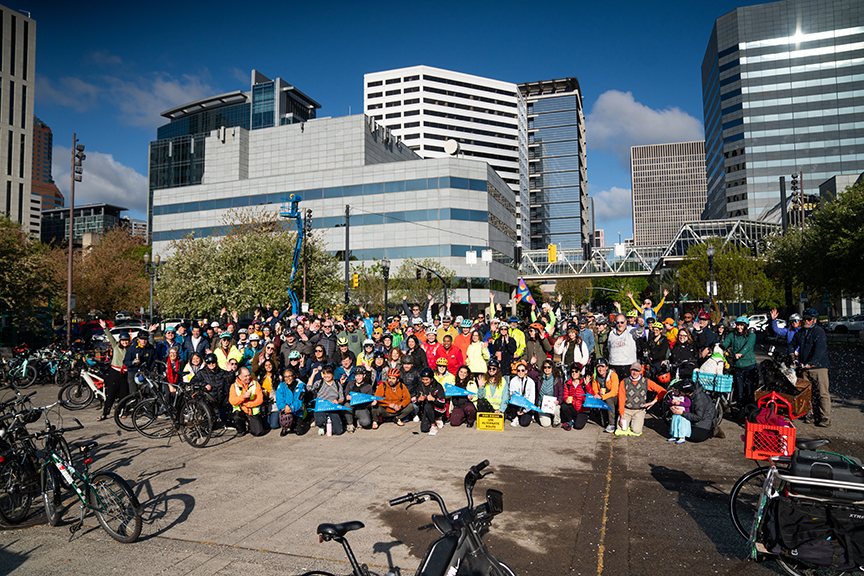 A bike bus group photo, including people and bikes with downtown Portland behind them