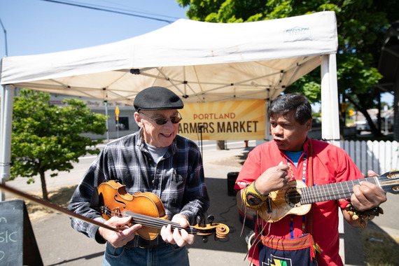 Violinist and ukulele player jam together at a farmers market.