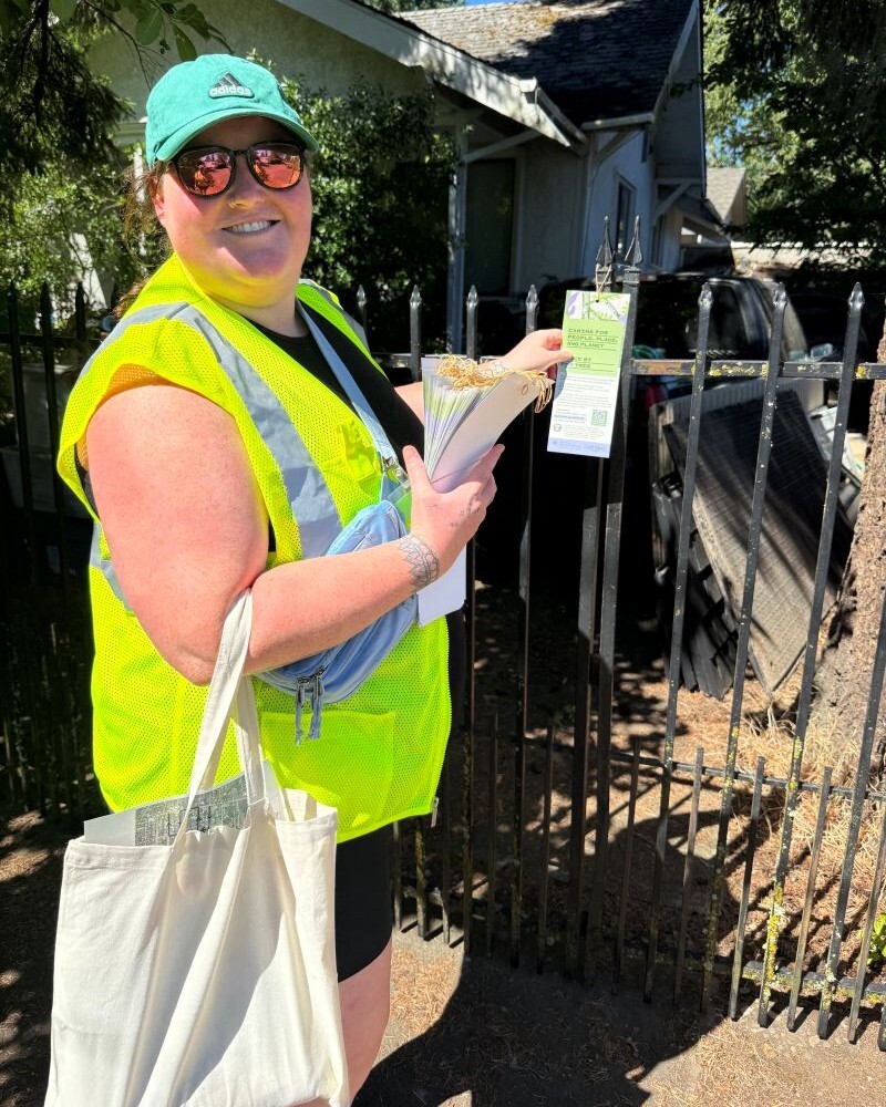 PPR _ person holding a doorhanger in front of a black gate