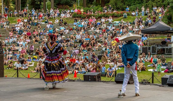 Two performers in Mexican folk dance attire in front of hundreds of people at Washington Park amphitheater