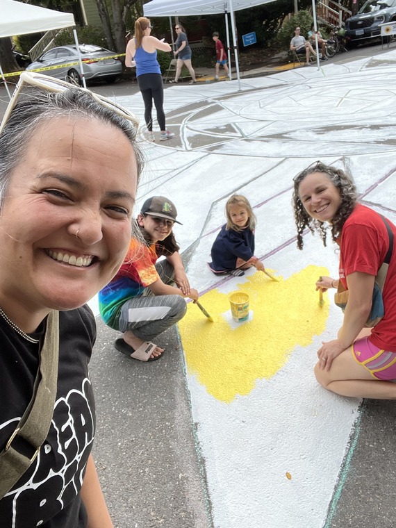 Councilor Koyama Lane with three people painting a section of street mural