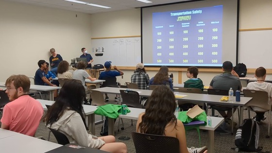 Two instructors leading 13 high school students in a transportation safety Jeopardy-style game. 