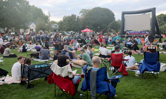 Movies in the Park - a crowd of people sit on the lawn of a park for Summer Free for All